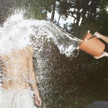 Девушка обливает себя водой из шланга